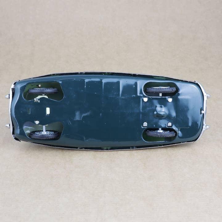 Giocattolo di latta retrò degli anni '50, macchina da corsa verde vista dal basso con chiave di carica.