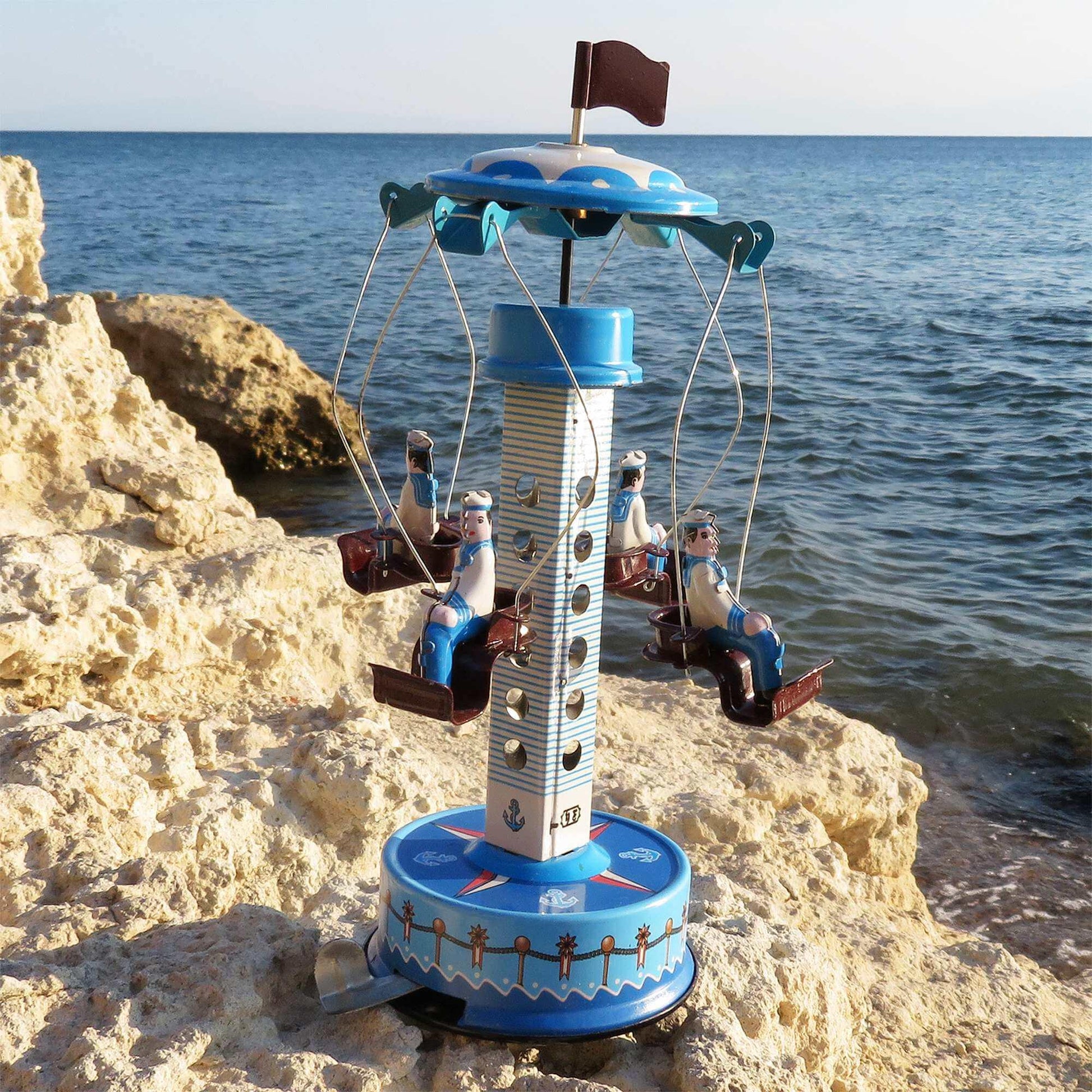 Met de hand opgewonden blikken carrousel Matrozen – Nostalgisch oud speelgoed aan de oever, met matrozenfiguren en zeevaartontwerp.